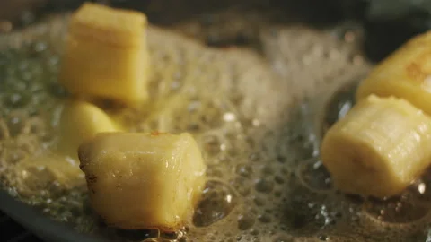 Cane brown sugar sprinkled on top of fried banana chunks 스톡 동영상 154146932