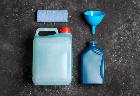 Canisters with motor oil and plastic funnel on grey table, top view Stock Photos