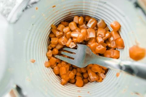Canned corn in a jar with a fork close-up. Stock Photos