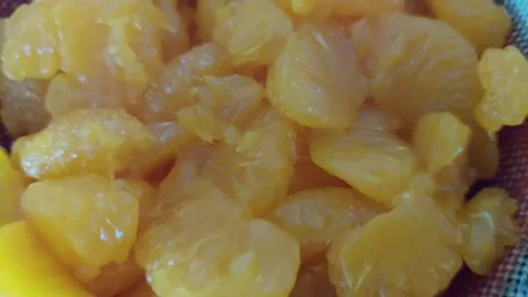 Canned mandarin orange segments in a sieve close up Stock Footage 334333053