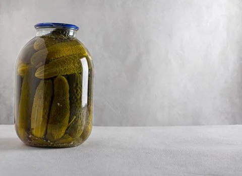 Canned pickled cucumbers in jars on a light background. Homemade food. Close- Stock Photos