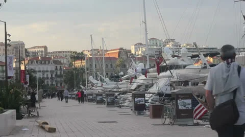 Cannes Pedestrians walk by the sea with huge sailing boats. Stock Footage
