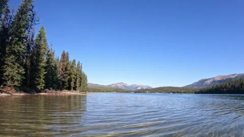 Canoe boating on a large mountain lake with small waves reflecting evergreen Stock Footage 320318665