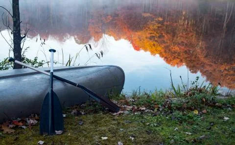 Canoe with a reflection of fall colored trees on the water behind it. Stock Photos