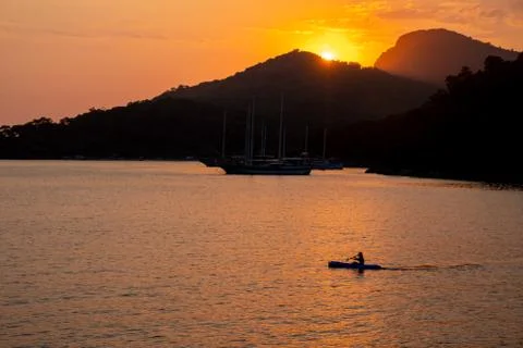 Canoe at sea while sun sets Stock Photos