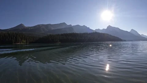 Canoeing across a mountain lake with small waes and the sun reflecting in the Stock Footage 320318699
