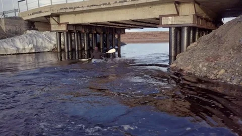 Canoeist sails upstream under bridge with supports in tundra Stock Footage 122493068
