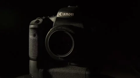 Canon DSLR camera rotates against black with directional side lighting Stock Footage 333475380