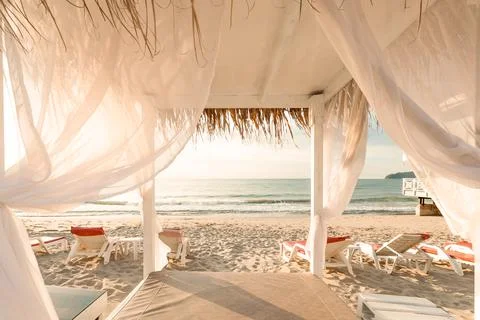 Canopy bed with white drapes on an empty beach Stock Photos