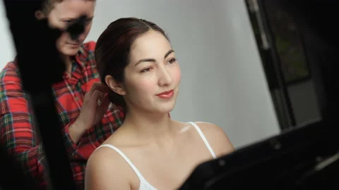 Canted, angled shot of model on photo shoot getting hair adjusted by hairstylist Stock Footage 193896541
