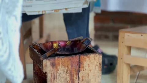 The "canting" tool for drawing batik is in a small frying pan on the stove Stock Footage 278438656