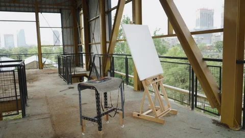 A canvas next to a table filled with paintings in a building Vídeos de archivo 264818068
