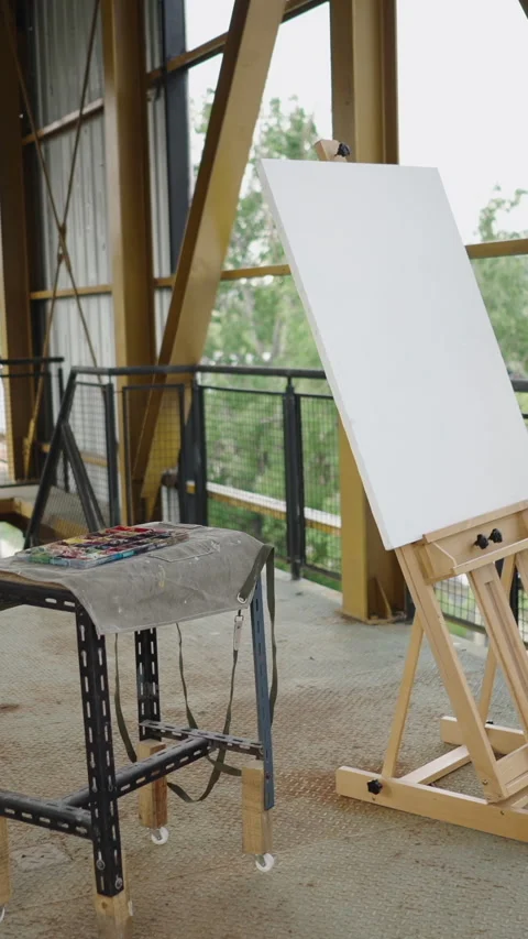 A canvas next to a table filled with paintings in a building Stock Footage 265569738