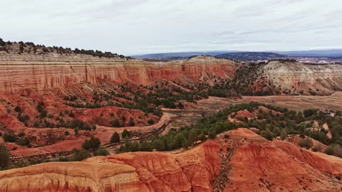 Canyon landscape with red rock formations and distant hills during overcast day Stock Footage 331976810