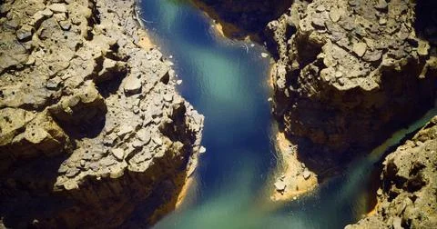 Canyon river winding through rugged terrain near a desert landscape Stock Illustration