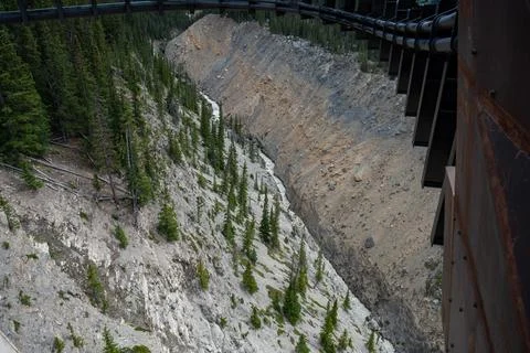 Canyon view with rock cliffs, river below, and bridge framework overhead. Stock Photos