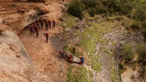 Canyoning group climing down a rope in  single file to abseiling spot Stock Footage 98233297