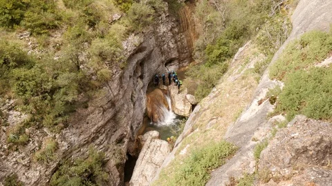 Canyoning group sliding down a small waterfall -wide shot Stock Footage 98218486