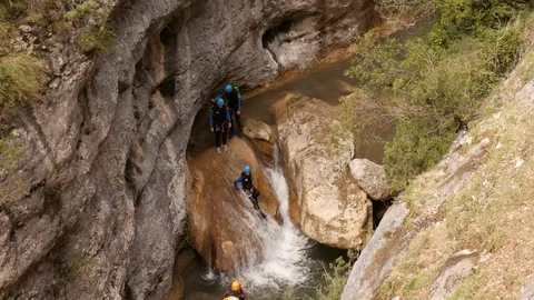 Canyoning group sliding down a small waterfall -medium shot Stock Footage 98218950