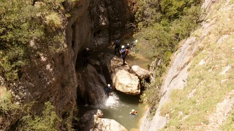 Canyoning group sliding down a small waterfall -medium shot Stock Footage 98267805