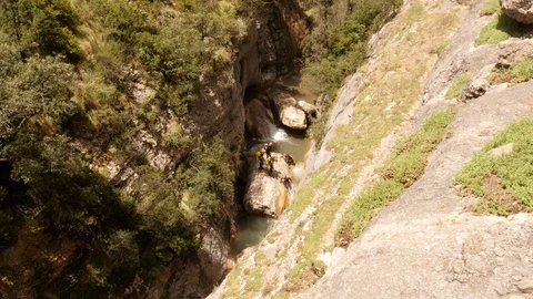 Canyoning group sliding down a small waterfall -wide shot Stock Footage 98284679