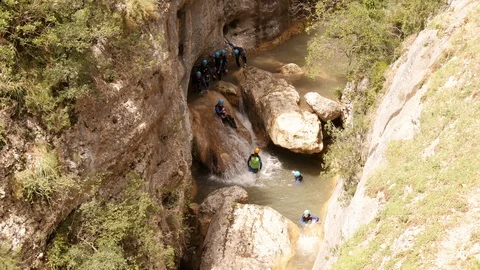 Canyoning group sliding down a  waterfall in single file Stock Footage 98294880