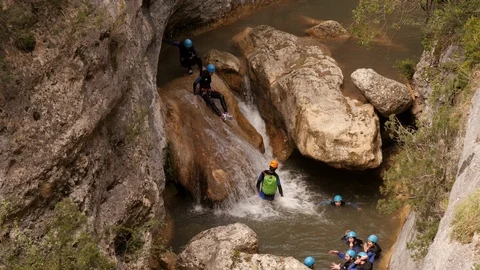 Canyoning group sliding down a waterfall – closer shot Stock Footage 98297390