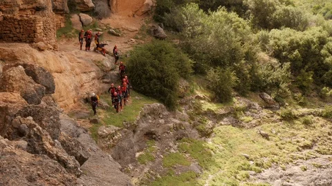 Canyoning group walking in single file to abseiling spot Stock Footage 98220566