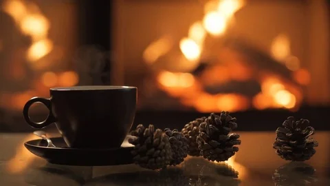 Cap of coffee on table in front of burning fireplace. Stock Footage
