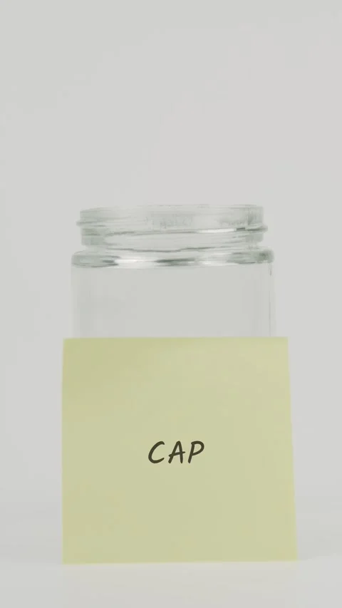 Cap text or word on yellow sticky note attached to glass jar with hand Stock Footage 311686994
