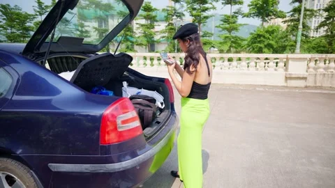 Cap wearing tourist does makeup outside parked vehicle Stock Footage 310286309