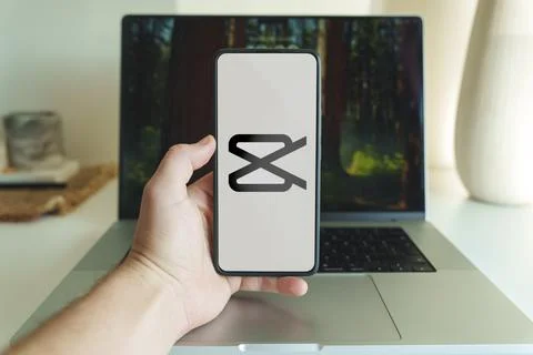 Capcut app logo on cellphone screen. Person holding capcut application on Stock Photos