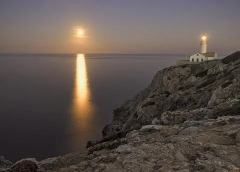 Capdepera lighthouse at dusk, with moonbeam on sea and rocks, mallorca, spain Stock Photos
