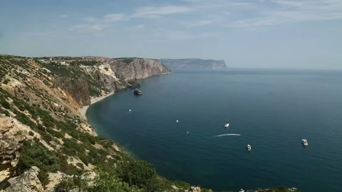 Cape surrounded by mountains covered with green vegetation. Yachts are sailing 库存影片 100908154