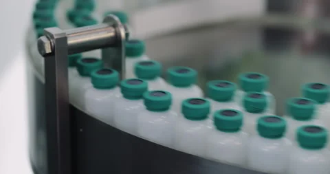 Capped plastic bottles circulate along rotary conveyor inside modern production Video stock 346227467