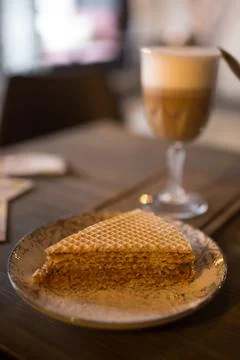 Cappuccino and a slice of cake on a table in a cafe. Stock Photos