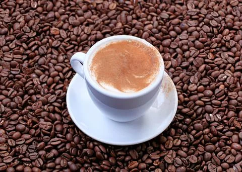 Cappuccino in coffee beans setting Stock Photos