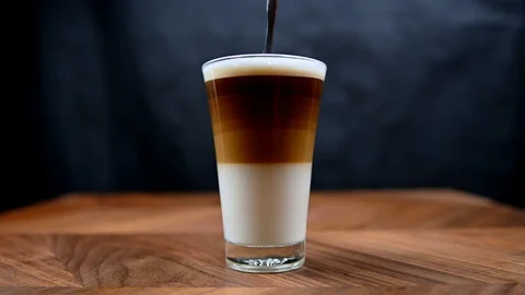 Cappuccino coffee layers getting stirred in glass cup Stock Footage 125768776