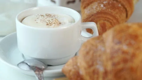 Cappuccino coffee is sprinkled cocoa on background of baked french croissants. Stock Footage 150491371