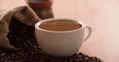 Cappuccino Cup with scattered Coffee beans and cezve coffee pot close up shot Stock Footage 98041657