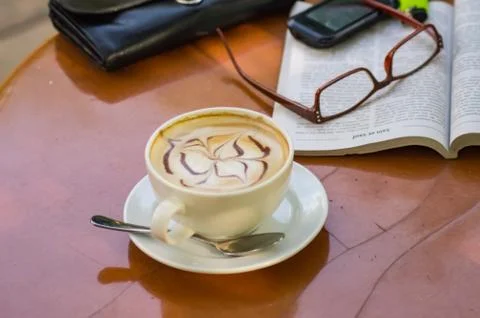 Cappuccino lying on a table with a book Stock Photos