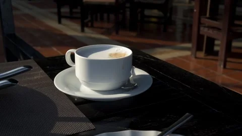 Cappuccino in white ceramic mug with coaster and stainless steel spoon on bl Stock Footage 275592373