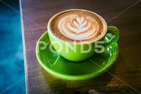Cappucino in a green cup and saucer with foram art in the shape of a leaf Stock Photos