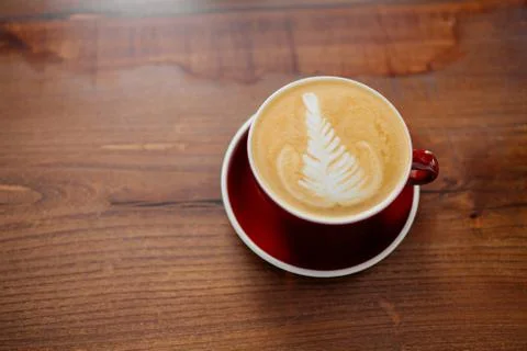 Cappucino in red cup on a table. Stock Photos