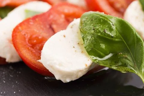 Caprese salad with mozzarella, tomato, basil and balsamic vinegar arranged on bl Stock Photos