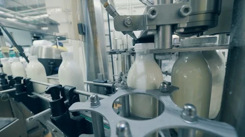 Caps of the bottles with milk are getting bound mechanically. Automated process Stock Footage 123354379