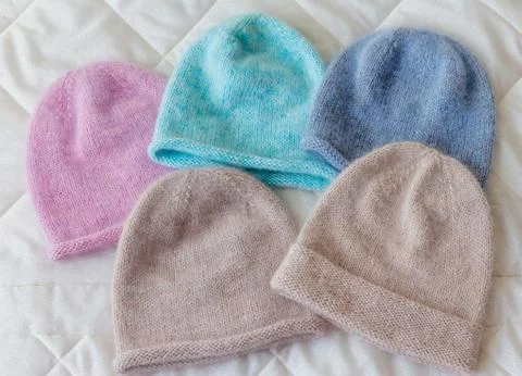 Caps of different colors on a rag background, knitted wool by hand on the spo Stock Photos