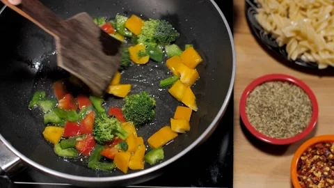Capsicum, broccoli, red and yellow bell peppers being stir-fried in a pan Stock Footage 157415040