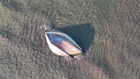 A capsized boat floating upside down in the open ocean 스톡 동영상 347816074