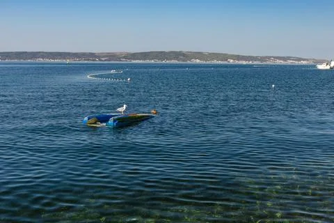 Capsized small boat with seagull drifting near the Croatian coast Stock Photos